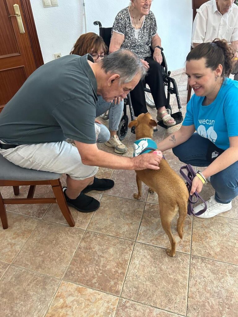 Residente acariciando a un perro de terapia junto a una profesional de WECAN Córdoba