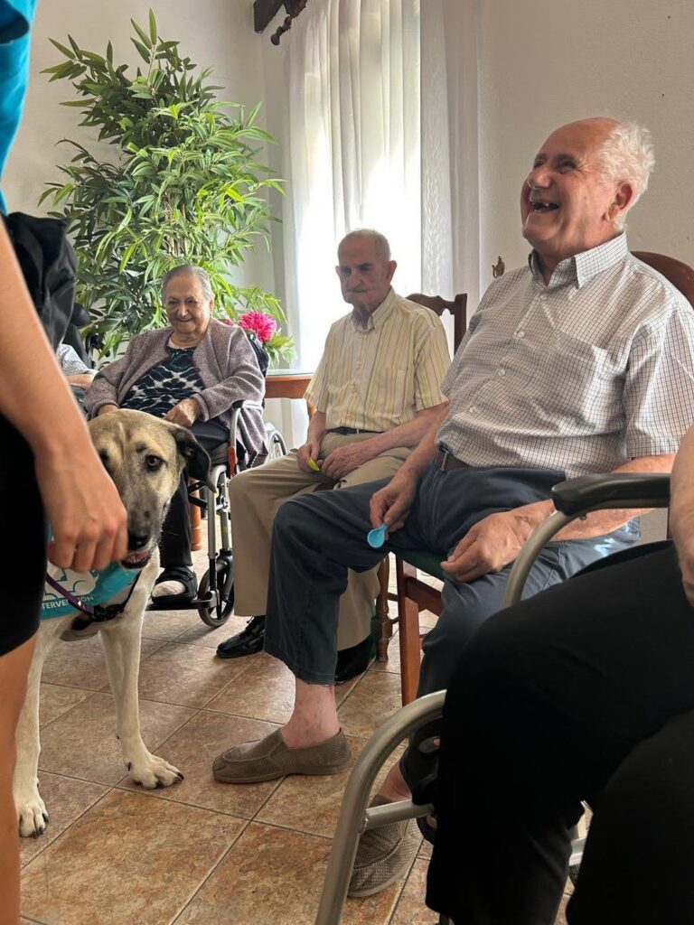 Residente sonriendo durante el taller de terapia con perros en la residencia